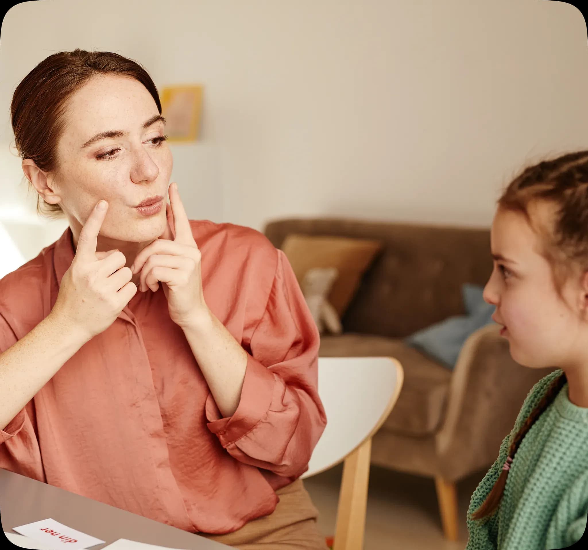 A speech therapist working with a young patient in a warm, welcoming room